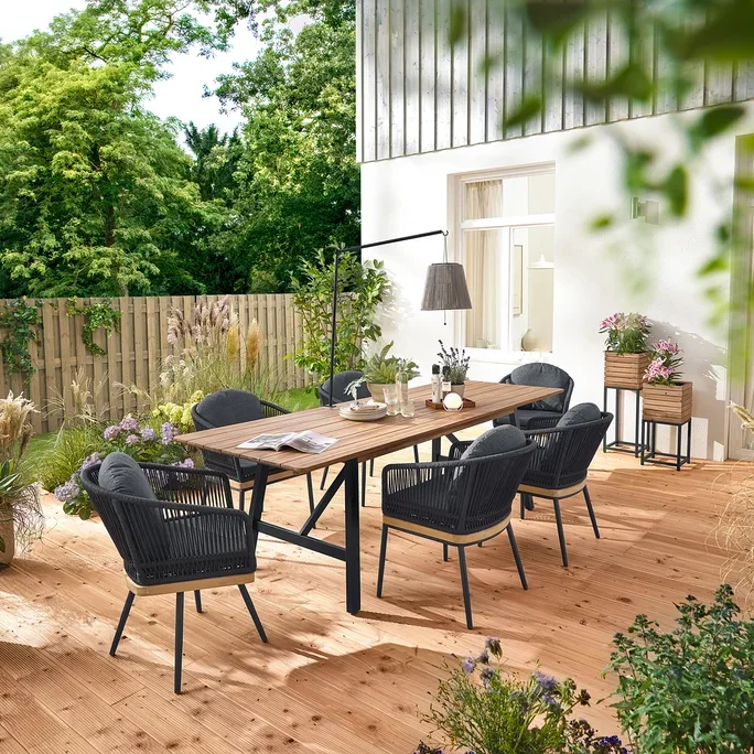 Auf einer Holzterrasse stehen ein ausziehbarer Gartentisch mit rustikalem Gestell, ca. 200-250 cm, drehbare Gartenstühle mit Textilgeflecht und Gartenstühle mit Textilgeflecht. Zwei Pflanzsäulen »Elin« und eine Akku-Solar-Laterne mit Tischhalterung sind ebenfalls zu sehen.