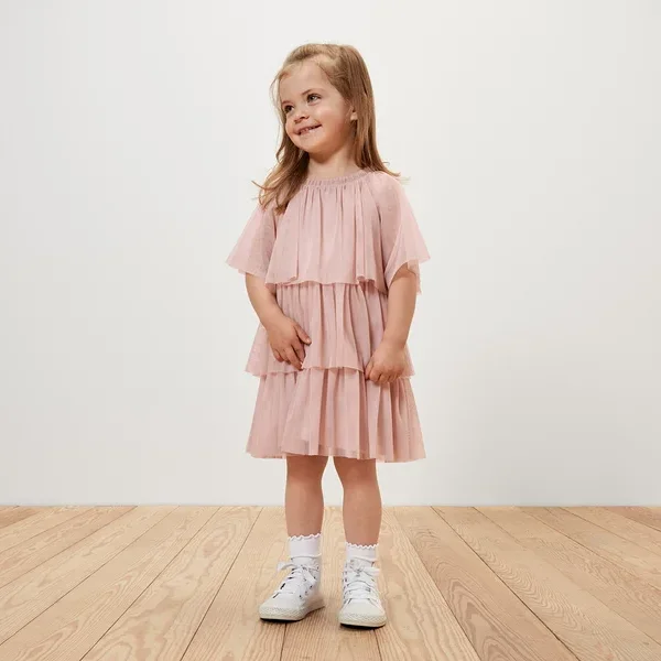Ein lächelndes Mädchen trägt ein Kinder-Tüllkleid.