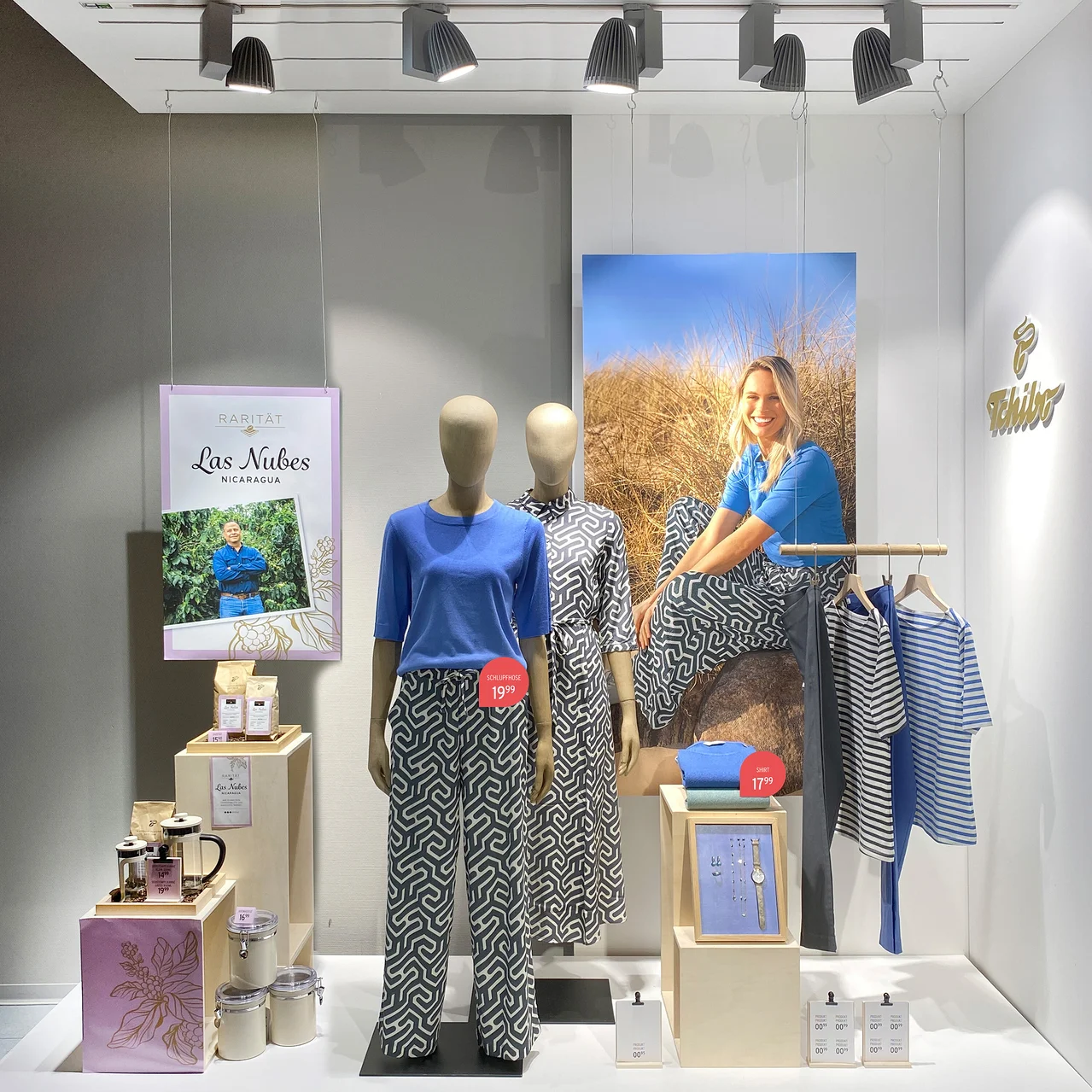 Schaufenster mit bekleideten Schaufensterpuppen und Kaffeeprodukten.