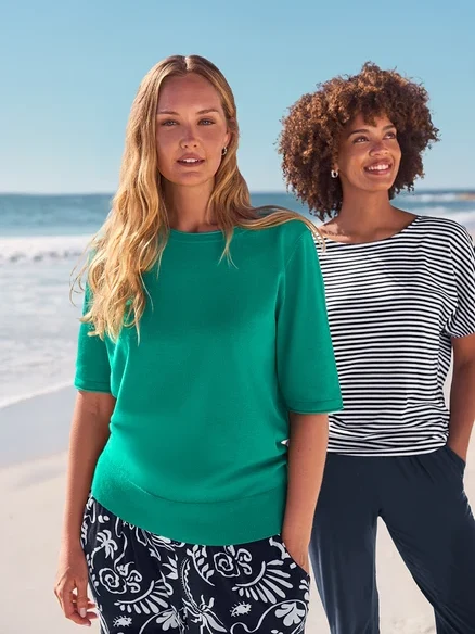 Zwei Frauen am Strand tragen Ohrstecker mit Glaskristallsteinen, Creolen Pavé und Da. 3/4-Jerseyhose, dunkelblau.