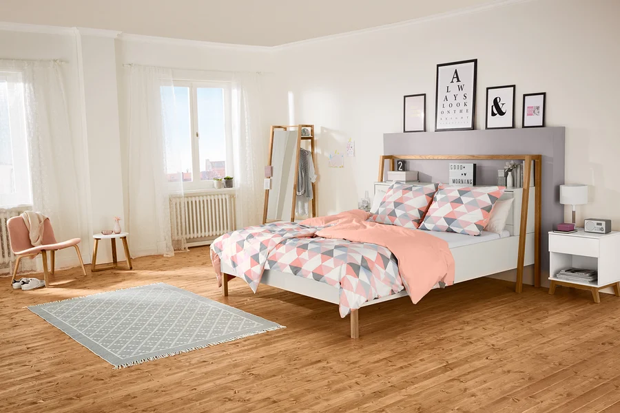 Schlafzimmer mit Bett, Nachttisch und Spiegel.