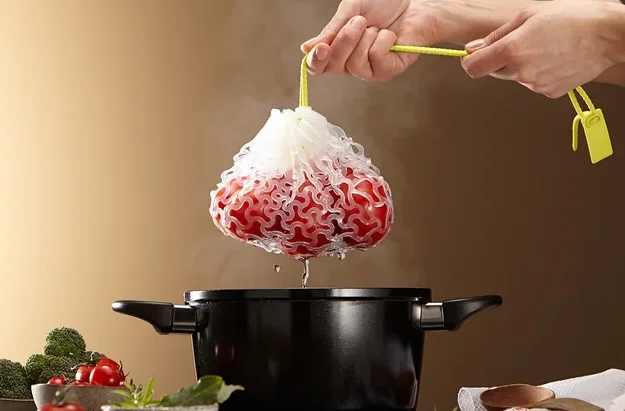 Hände halten einen Beutel mit roten Beeren über einen Topf.