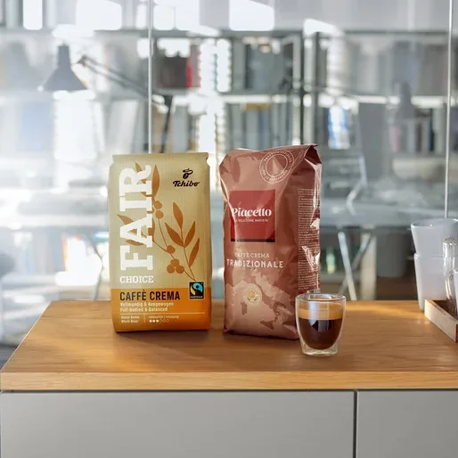 Zwei Kaffeepackungen und eine Tasse Espresso auf einer Holzplatte in einem modernen Büro.