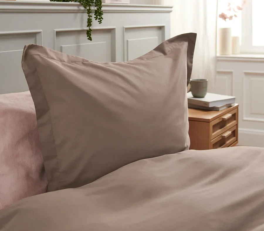 Detailaufnahme von brauner Tencel™-Baumwoll-Bettwäsche auf einem Bett mit rosa Laken.