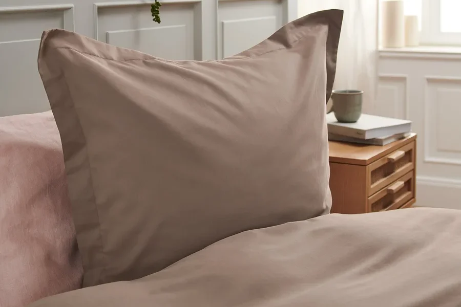 Detailaufnahme von brauner Tencel™-Baumwoll-Bettwäsche auf einem Bett mit rosa Laken.