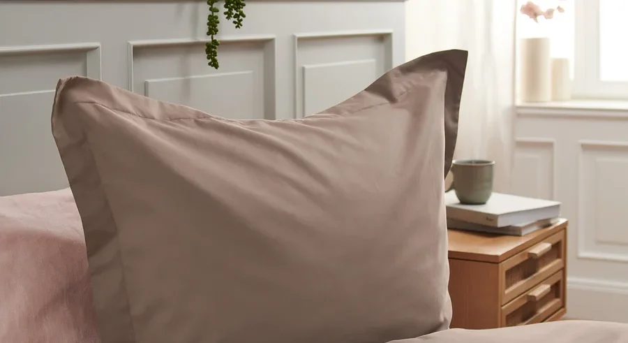 Detailaufnahme von brauner Tencel™-Baumwoll-Bettwäsche auf einem Bett mit rosa Laken.