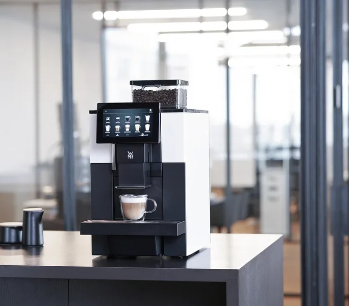 WMF 950 S Profi-Kaffeevollautomat mit Tasse Cappuccino auf einem Tisch.