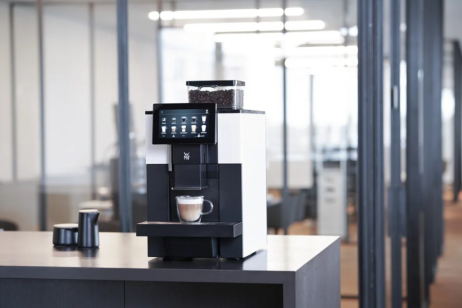 WMF 950 S Profi-Kaffeevollautomat mit Tasse Cappuccino auf einem Tisch.