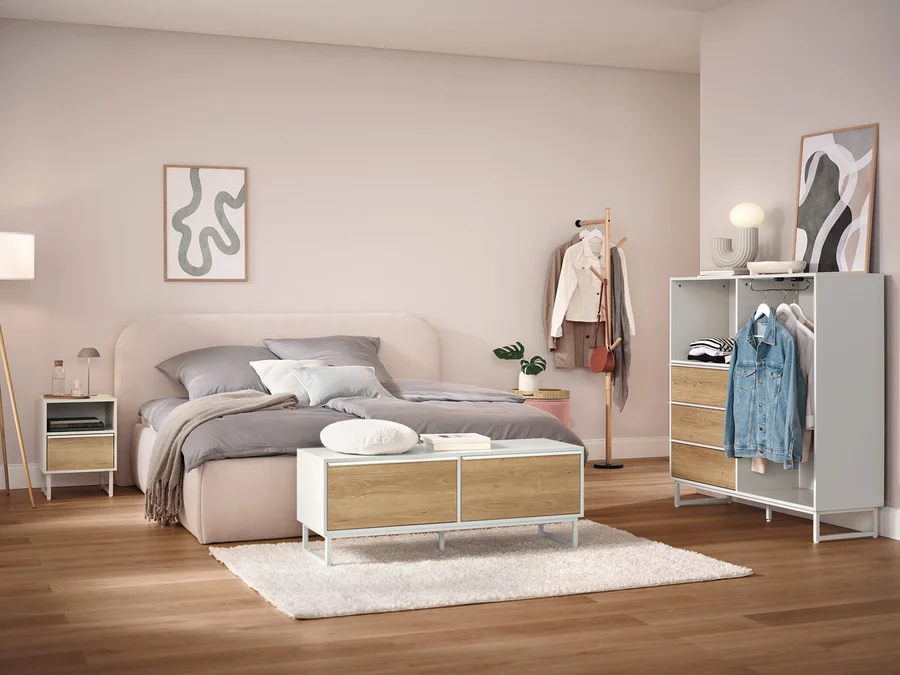 Schlafzimmer mit Bett, Nachttisch, Schrank und Kleiderständer.