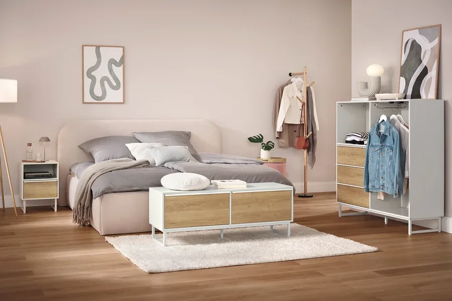 Schlafzimmer mit Bett, Nachttisch, Schrank und Kleiderständer.