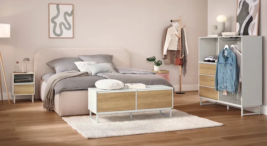 Schlafzimmer mit Bett, Nachttisch, Schrank und Kleiderständer.