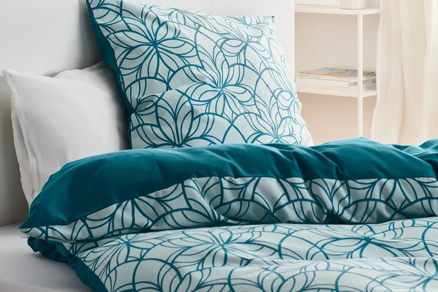 Bett mit Biber-Bettwäsche, Normalgröße, mit Blumenmuster und unifarbenem Rand.