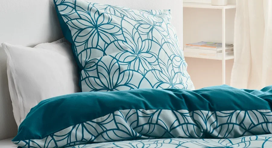 Bett mit Biber-Bettwäsche, Normalgröße, mit Blumenmuster und unifarbenem Rand.