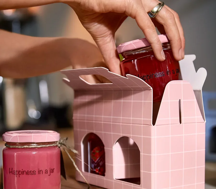 Eine Frau legt ein Glas mit Schraubverschluss in eine Gläser-Geschenkverpackung.