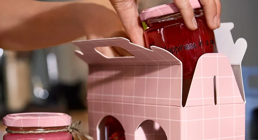 Eine Frau legt ein Glas mit Schraubverschluss in eine Gläser-Geschenkverpackung.