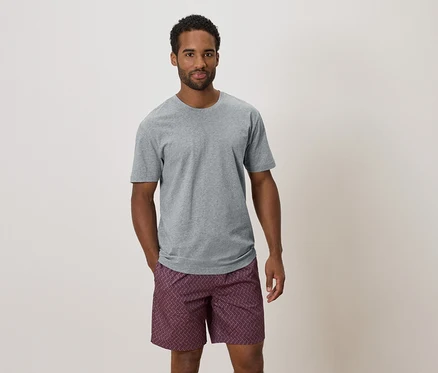 Mann mit grauem T-Shirt und gemusterter Shorts