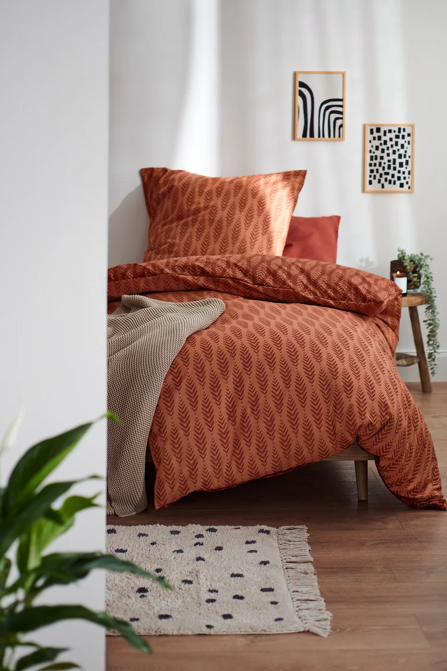 Terrakottafarbene Premium-Baumwoll-Bettwäsche in Normalgröße mit Blattmuster auf einem Bett.