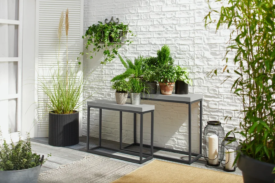 Auf einer Terrasse stehen zwei Konsolentische mit Betonplatten, die mit Topfpflanzen dekoriert sind.