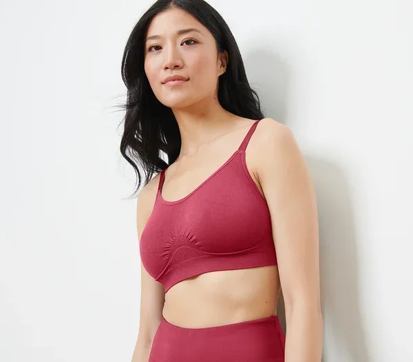 Asiatische Frau trägt einen nahtlosen Sport-BH in Beere-Farbe und schaut nach rechts.