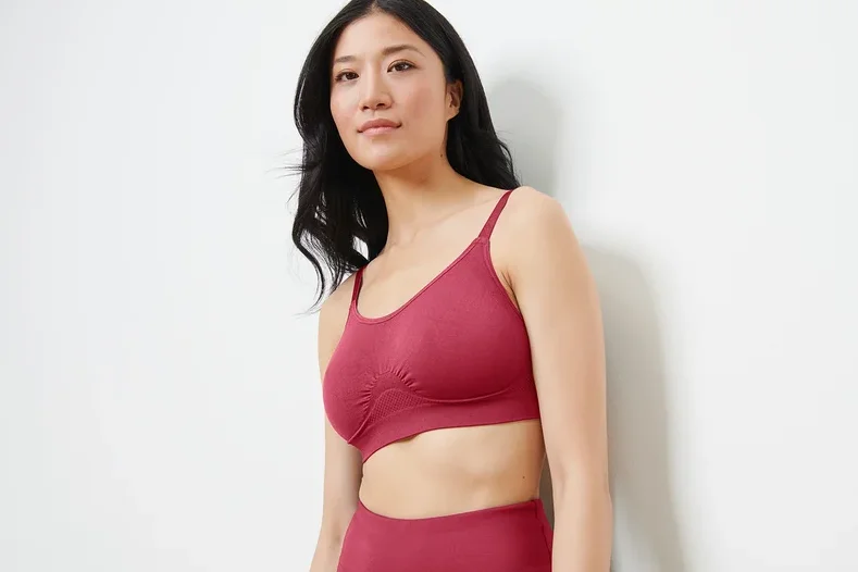 Asiatische Frau trägt einen nahtlosen Sport-BH in Beere-Farbe und schaut nach rechts.
