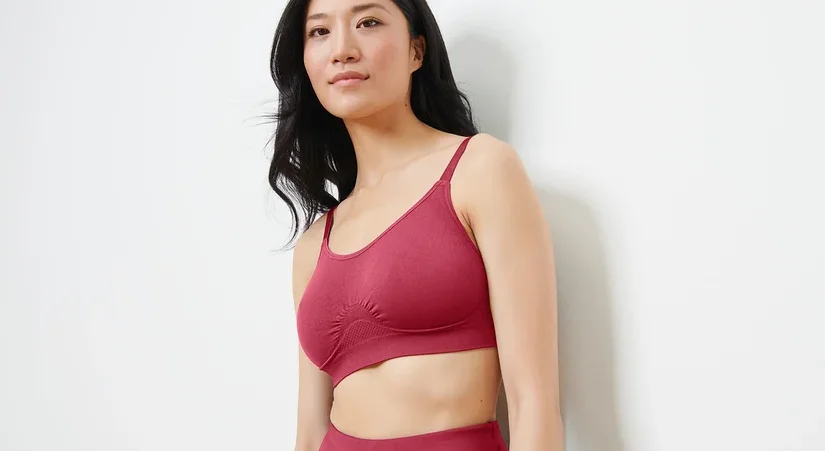 Asiatische Frau trägt einen nahtlosen Sport-BH in Beere-Farbe und schaut nach rechts.