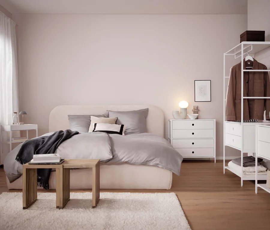 Schlafzimmer mit Bett, Kommode und grauer LED-Akku-Tischleuchte.