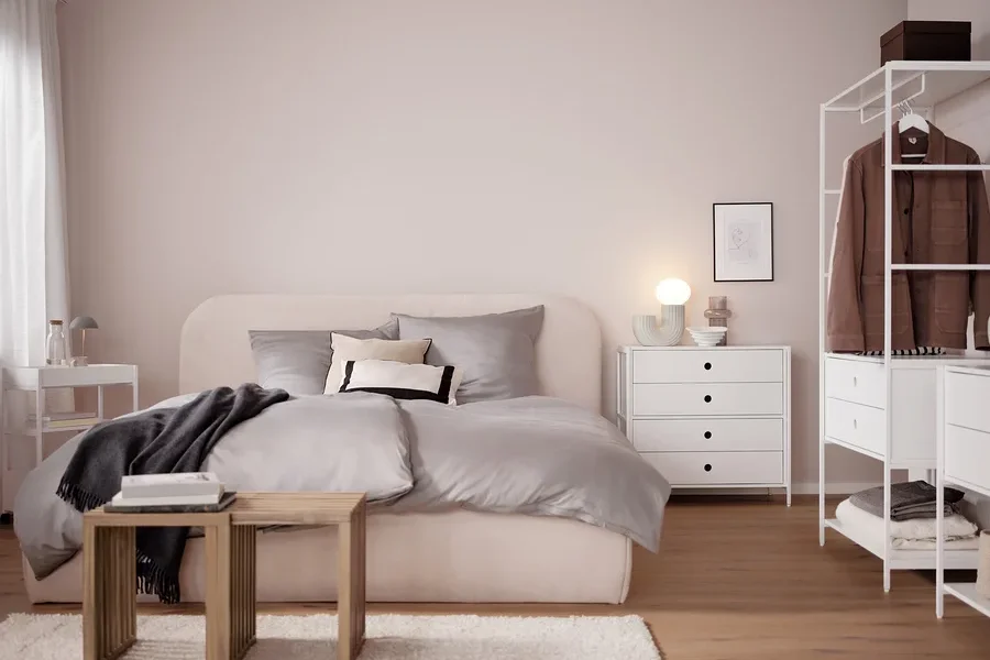 Schlafzimmer mit Bett, Kommode und grauer LED-Akku-Tischleuchte.
