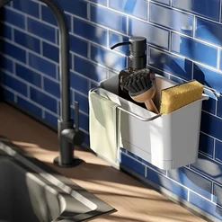 Küchenspüle mit schwarzem Wasserhahn und einem weißen Spülutensilienhalter an blauen Fliesen. Der Halter enthält einen Seifenspender, eine Bürste, einen Schwamm und ein Tuch.