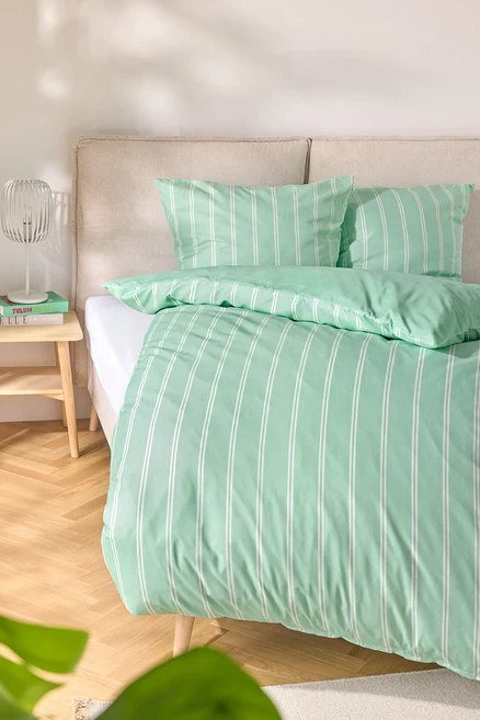 Bett mit hellgrüner Microfaser-Bettwäsche, Normalgröße und Übergröße, mit weißen Streifen.