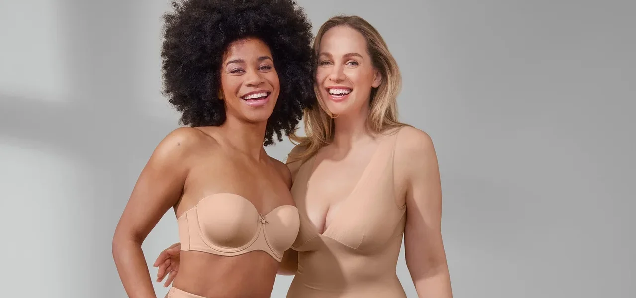 Zwei lächelnde Frauen posieren. Eine trägt einen Multistyle-BH und beige Shorts »Shaping«. Die andere trägt ein beiges Unterkleid »Shaping«.