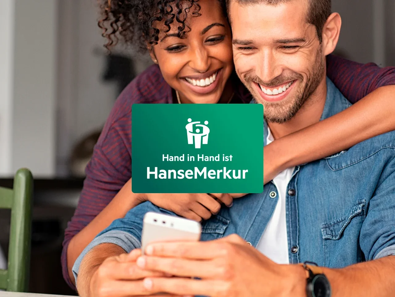 Ein lächelndes Paar schaut auf ein Mobiltelefon, die Frau umarmt den Mann.