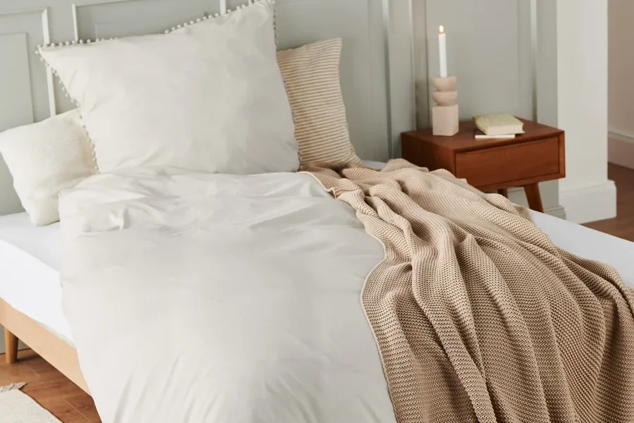 Beige Premium-Baumwoll-Bettwäsche in Normalgröße und Übergröße auf einem Bett.