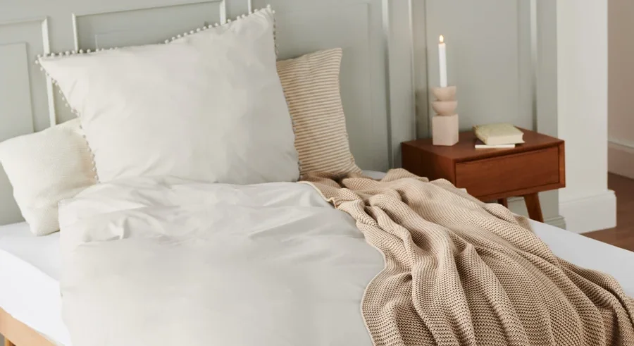 Beige Premium-Baumwoll-Bettwäsche in Normalgröße und Übergröße auf einem Bett.