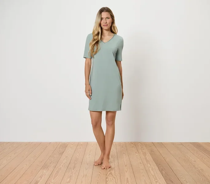 Eine Frau steht auf einem Holzboden und trägt ein hellgrünes Kleid.
