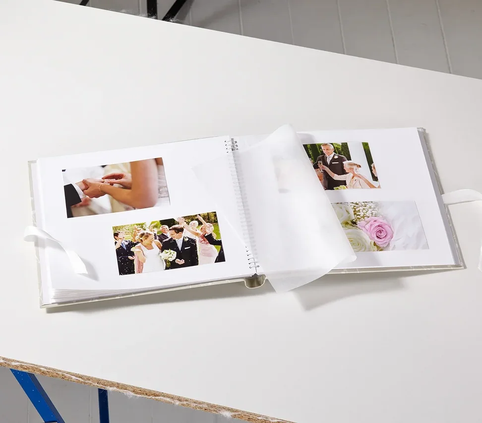 Geöffnetes Hochzeitsalbum mit Fotos auf einem weißen Tisch.