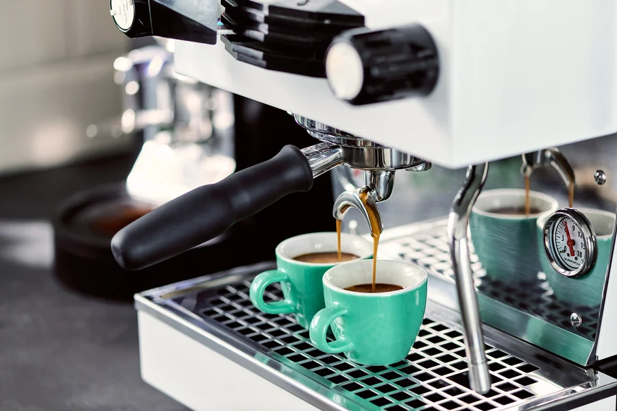 Espressomaschine befüllt zwei grüne Tassen mit Kaffee.
