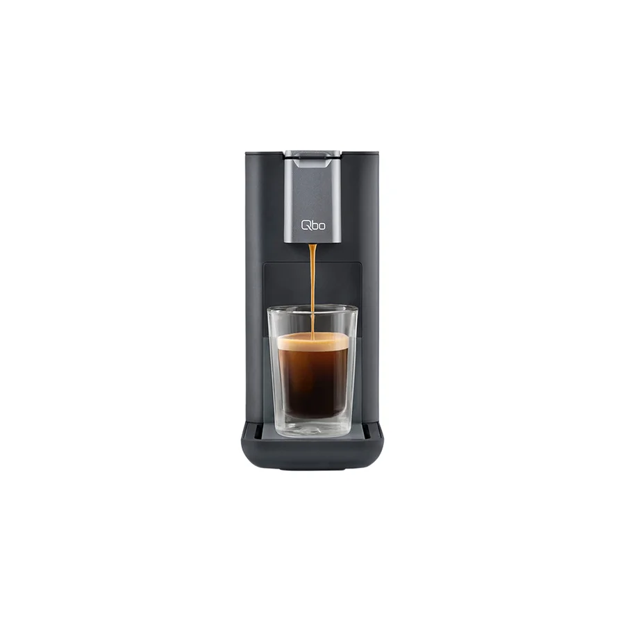 Kaffee läuft aus einer grauen Qbo-Kaffeemaschine in ein Glas.