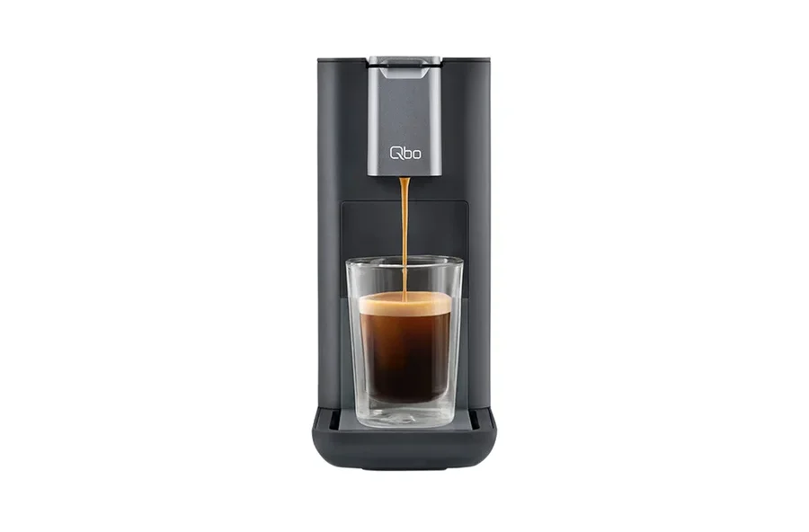Kaffee läuft aus einer grauen Qbo-Kaffeemaschine in ein Glas.
