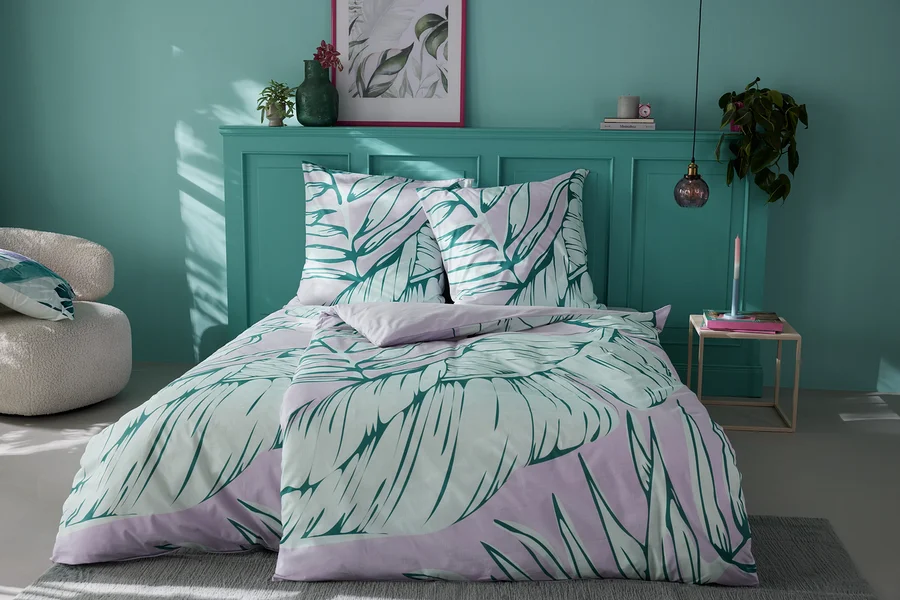 Bett mit Renforcé-Bettwäsche mit Blättermotiv.