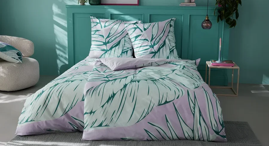 Bett mit Renforcé-Bettwäsche mit Blättermotiv.
