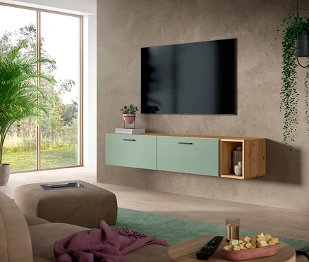 Modernes Wohnzimmer mit großem Fernseher an grauer Wand über einer grünen xonox Wohnwand »The One«. Die Wohnwand hat zwei grüne Schubladen und ein offenes Holzregal. Im Vordergrund stehen ein braunes Sofa, ein Ottoman und ein runder Couchtisch mit Snacks.