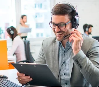 Mann mit Headset lächelt und hält Klemmbrett im Büro.