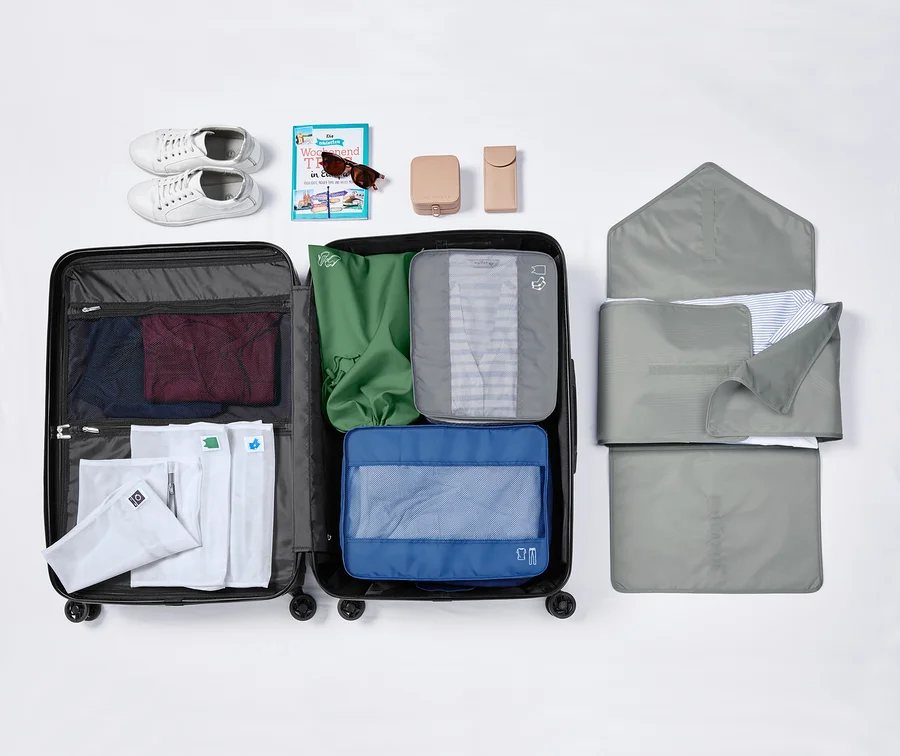 Offener Koffer mit Kleidung, Schuhen, Sonnenbrille und Toilettenartikeln.