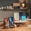 Verschiedene Kaffeepackungen und zwei Gläser mit Kaffee stehen auf einer Küchentheke.