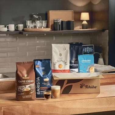 Verschiedene Kaffeepackungen und zwei Gläser mit Kaffee stehen auf einer Küchentheke.