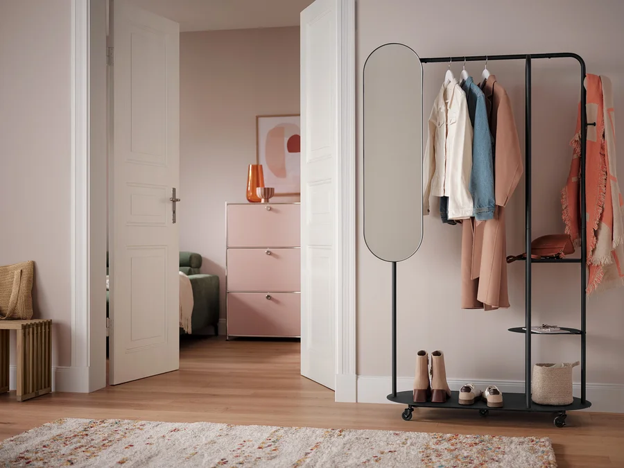 Zimmer mit Ausziehbank, Schuhen und Kleidung auf einem Kleiderständer.