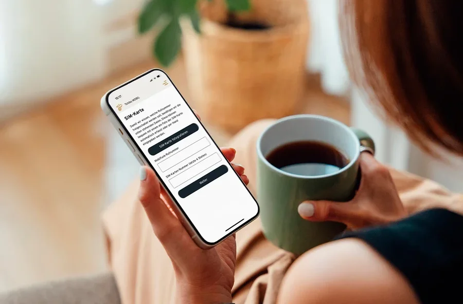 Frau hält eine Tasse Kaffee und schaut auf ihr Handy.