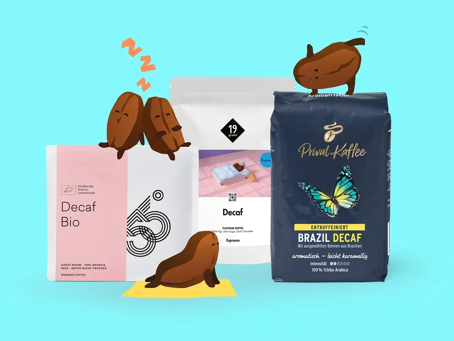 Drei Packungen entkoffeinierten Kaffees auf hellblauem Hintergrund. Die pinke „Decaf Bio“-Packung hat zwei schlafende Kaffeebohnen und eine schlafende Seehund-Bohne. Eine weiße „Decaf Espresso“-Packung ist in der Mitte, und eine dunkelblaue „Privat Kaffee Brazil Decaf“-Packung hat eine springende Kaffeebohne oben.