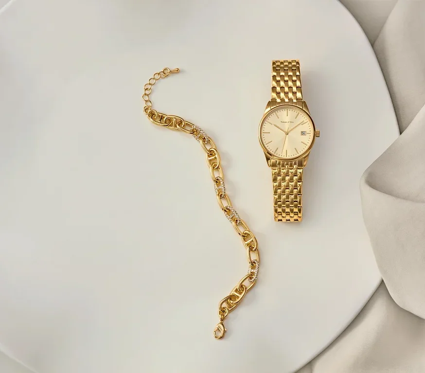 Goldenes Armband und goldene Uhr auf einem weißen Teller.