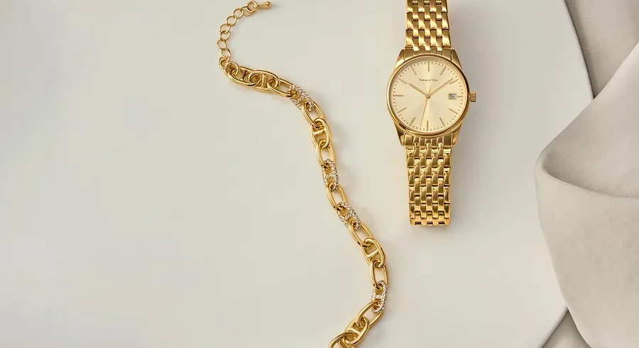 Goldenes Armband und goldene Uhr auf einem weißen Teller.